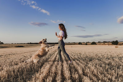 Mid adult woman with dog on agricultural field