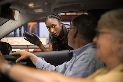 Sales staff guiding customers sitting in car at hardware store