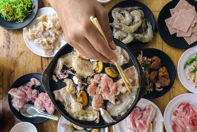 Bbq barbecue eating. people grilling  pork, meal, shellfish and shrimp with wooden chopsticks.