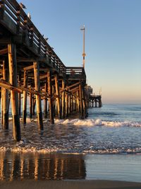 Pier on sea against clear sky at sunset