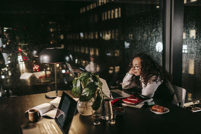 Midsection of woman using phone while sitting on table in restaurant