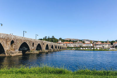 Arch bridge over river against clear blue sky