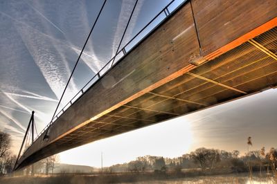 Low angle view of suspension bridge over river against sky