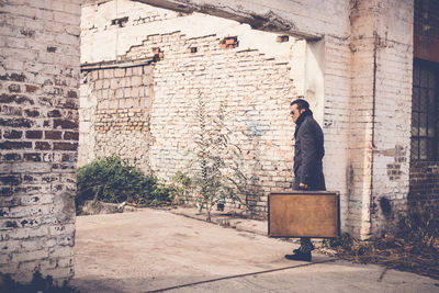 Full length of man standing against building wall