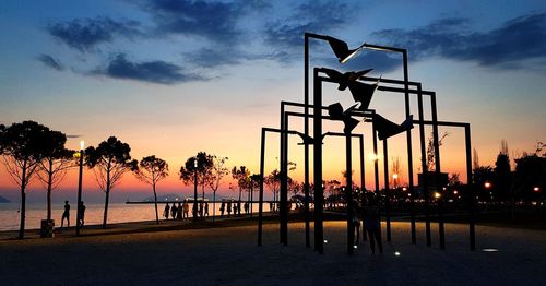 Silhouette people by trees against sky during sunset