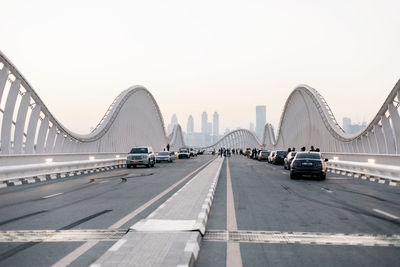 Cars on bridge against sky in city