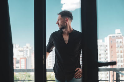 Young man looking away while standing in balcony