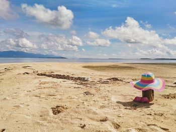 Woman with umbrella on beach against sky