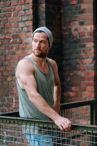 Portrait of man standing against brick wall