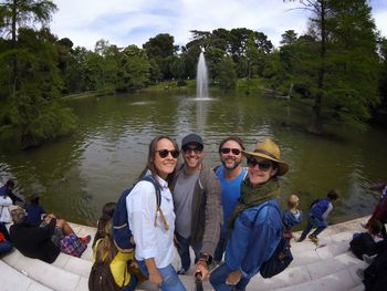 Portrait of friends taking selfie against lake by palacio de cristal