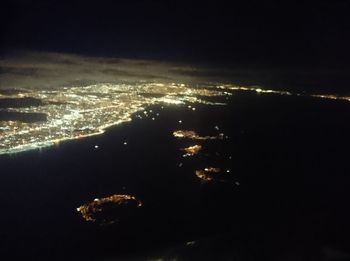 Aerial view of illuminated beach against sky at night