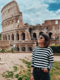 Full length of young woman standing against historic building