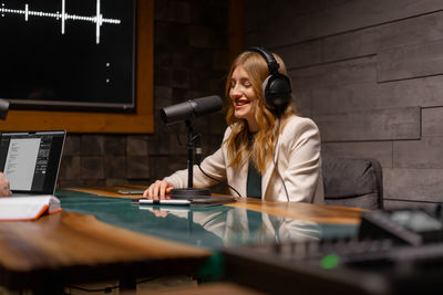 Closeup of young woman in headphones using microphone while working