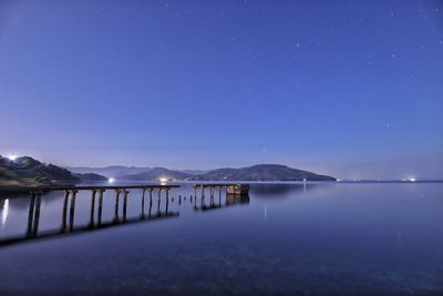 Scenic view of lake against clear blue sky at night