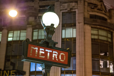 Close-up of illuminated light bulb hanging in city