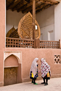 Rear view of women walking in basket against building