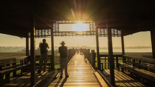 Rear view of people standing on footbridge over sea