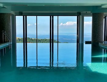 Swimming pool by sea against sky seen through window