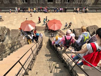 High angle view of people sitting on sidewalk in city