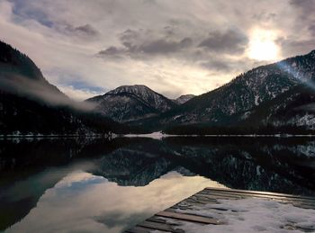 Scenic view of lake by mountains against cloudy sky