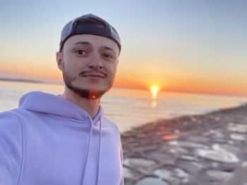 Portrait of man on beach against sky during sunset