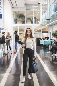 Portrait of smiling young female student standing in cafeteria at university