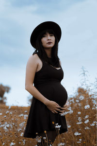 Portrait of pregnant woman standing on field