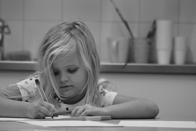 Close-up of girl writing on paper at table