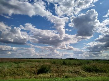 Scenic view of grassy field against cloudy sky