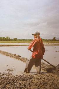 Farmer working on field against sky