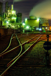 Railroad tracks in city against sky at night