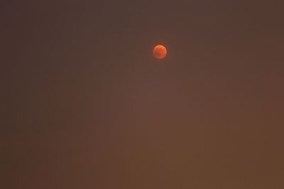 Low angle view of moon against orange sky