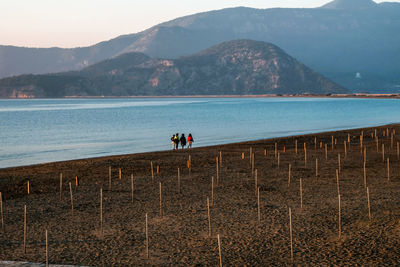 People on lake against mountains