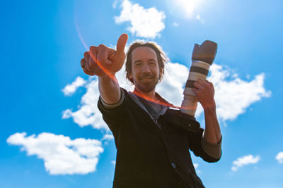 Low angle view of person holding umbrella against sky