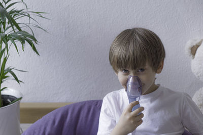 Unwell kid with chamber inhaler for cough treatment . healthcare and medication.