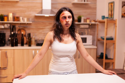 Young woman looking away while sitting at home