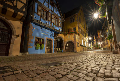 Street amidst illuminated buildings in city at night