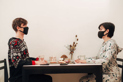 Side view of mother and daughter sitting on table