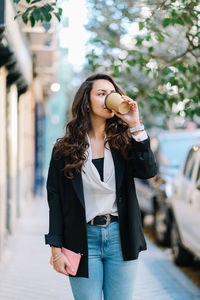 Young woman using phone while standing on street