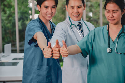 Portrait of smiling doctors gesturing while standing at hospital