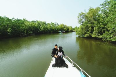 Couple sitting on boat sailing in river