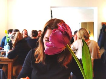 Portrait of young woman's face covered by flower