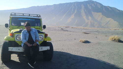 Man sitting on land by mountains