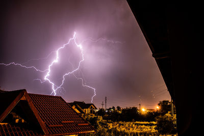 Low angle view of lightning over buildings at night