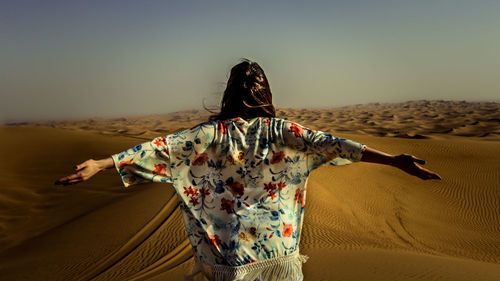Rear view of woman standing on desert