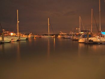Sailboats moored on sea against sky at night