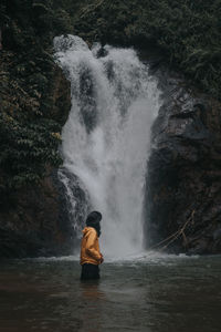 Side view of man standing against waterfall