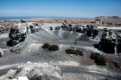 Panoramic view of rocks on shore against sky