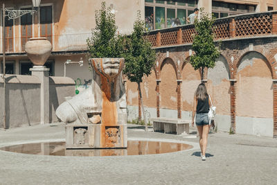 Rear view of woman standing against building