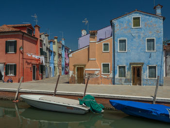 Sailboats moored on canal by buildings against sky